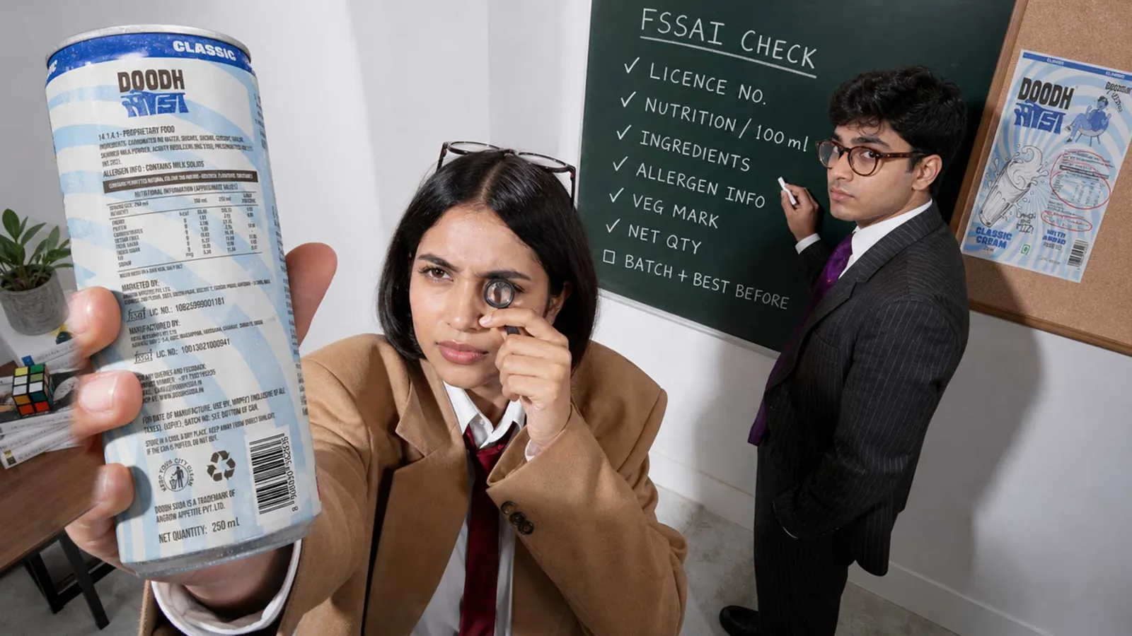 Person inspecting the back label of a Doodh Soda can, with an FSSAI label checklist written on a chalkboard behind