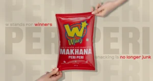 Hand-held red snack pouch of Wlue’s Peri Peri Makhana with bold logo and health claims, designed by DN Designs branding agency